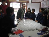 FOTO del MES: en matemáticas realizaron una gran tabla de multiplicar con carteles de supermercado. En la foto: Pablo y Pauline, alumna francesa en práctica, con los niños de Básica Chica FOTOMES